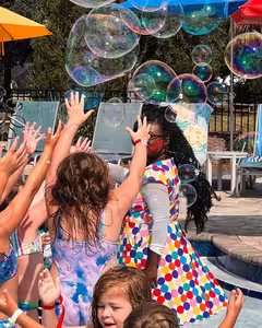 Children reaching for giant bubbles at a poolside family party at Splash RV Resort