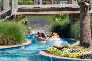 Guests floating the lazy river under the waterfall bridge at Splash RV Resort