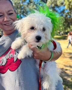 A small white dog held by a smiling guest at a pet event at Splash RV Resort in Milton, Florida