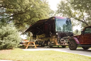 Large Class A motorhome parked on a concrete pad at a big rig friendly RV site shaded by trees at Splash RV Resort near Pensacola