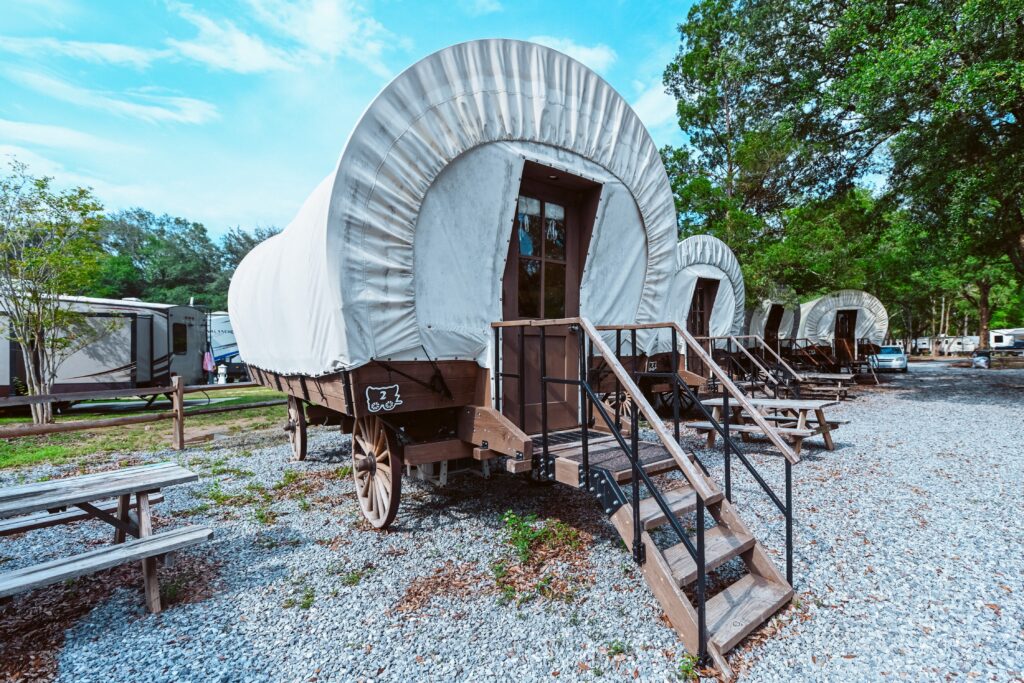 Conestoga covered-wagon glamping units on gravel sites at Splash RV Resort near Navarre Beach