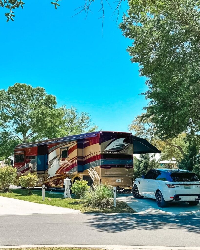 A Class A motorhome parked at a paved full-hookup RV site with an awning at Splash RV Resort in Milton, Florida