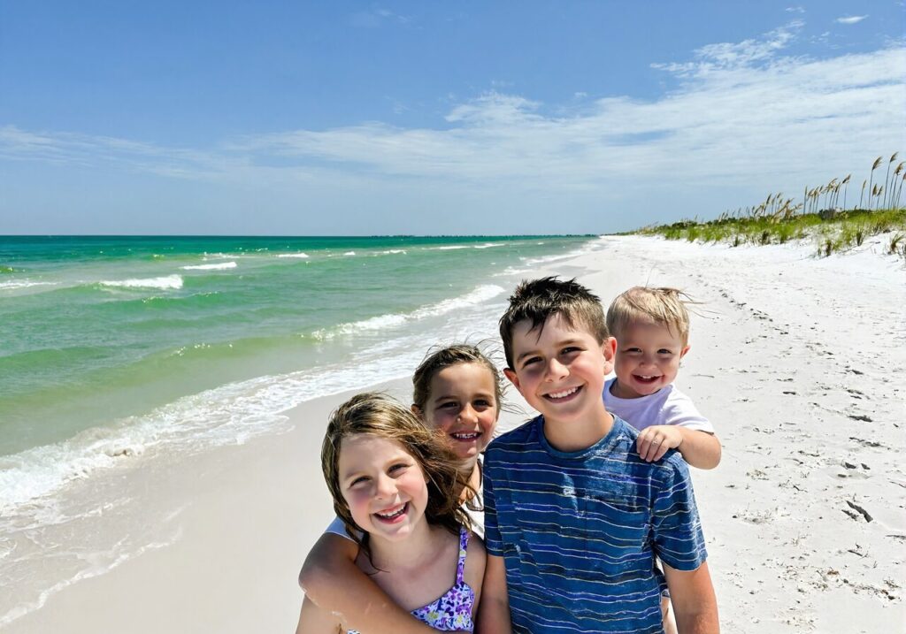 Family on the white sand and emerald water of a Gulf Coast beach near Navarre and Pensacola