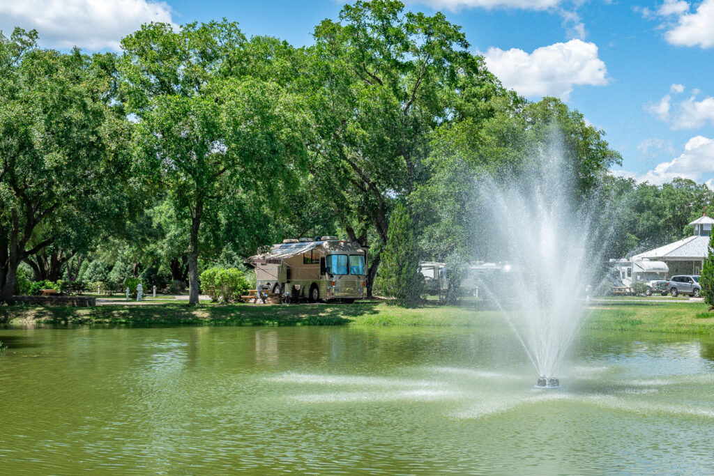 Big rig RV parked at a shaded lakeside site with a fountain at Splash RV Resort near Pensacola