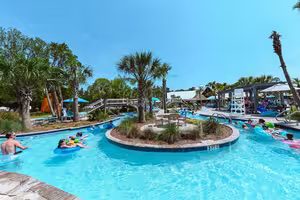 Guests floating in tubes on the lazy river at Splash RV Resort in Milton, Florida, with palm trees and water slides