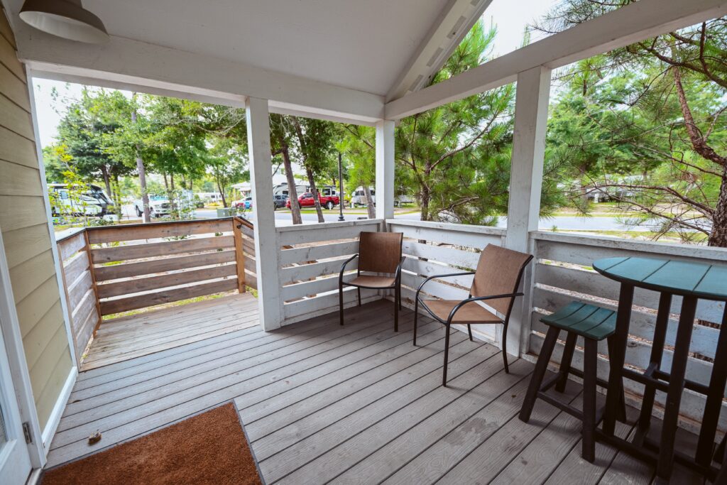 Covered cottage porch with chairs and bistro table overlooking the resort at Splash RV Resort near Pensacola