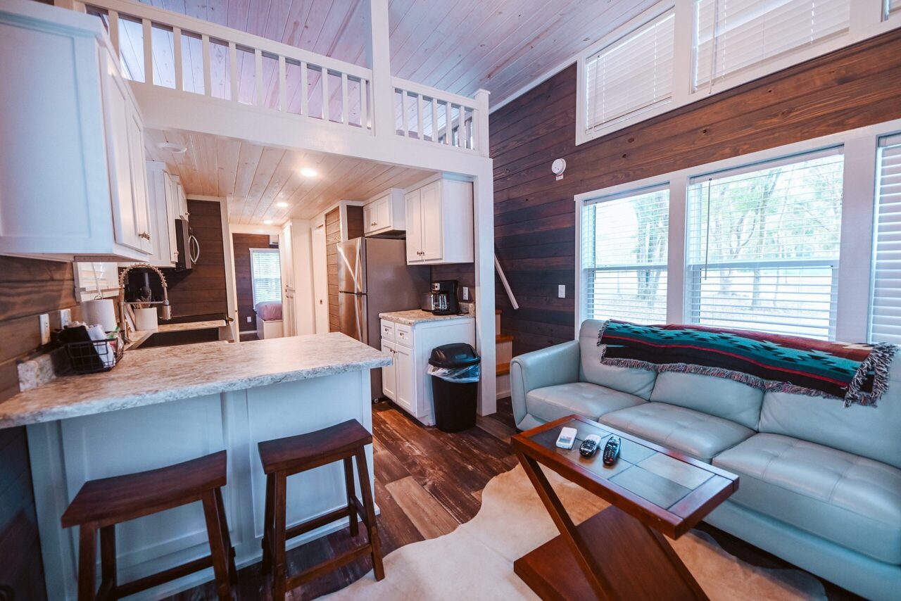 Cabin living area with a loveseat and open loft bedroom at Splash RV Resort near Navarre Beach