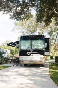 A big rig RV parked on a concrete full-hookup site under shade trees at Splash RV Resort in Milton FL
