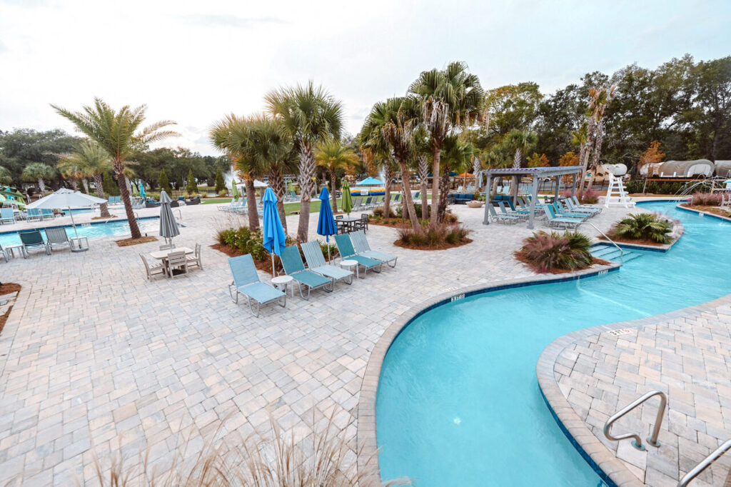 Lazy river winding past the pool and palm trees at Splash RV Resort near Pensacola