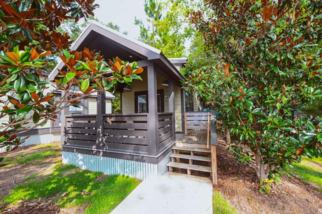 Modern luxury cottage with a covered porch tucked among magnolia trees at Splash RV Resort