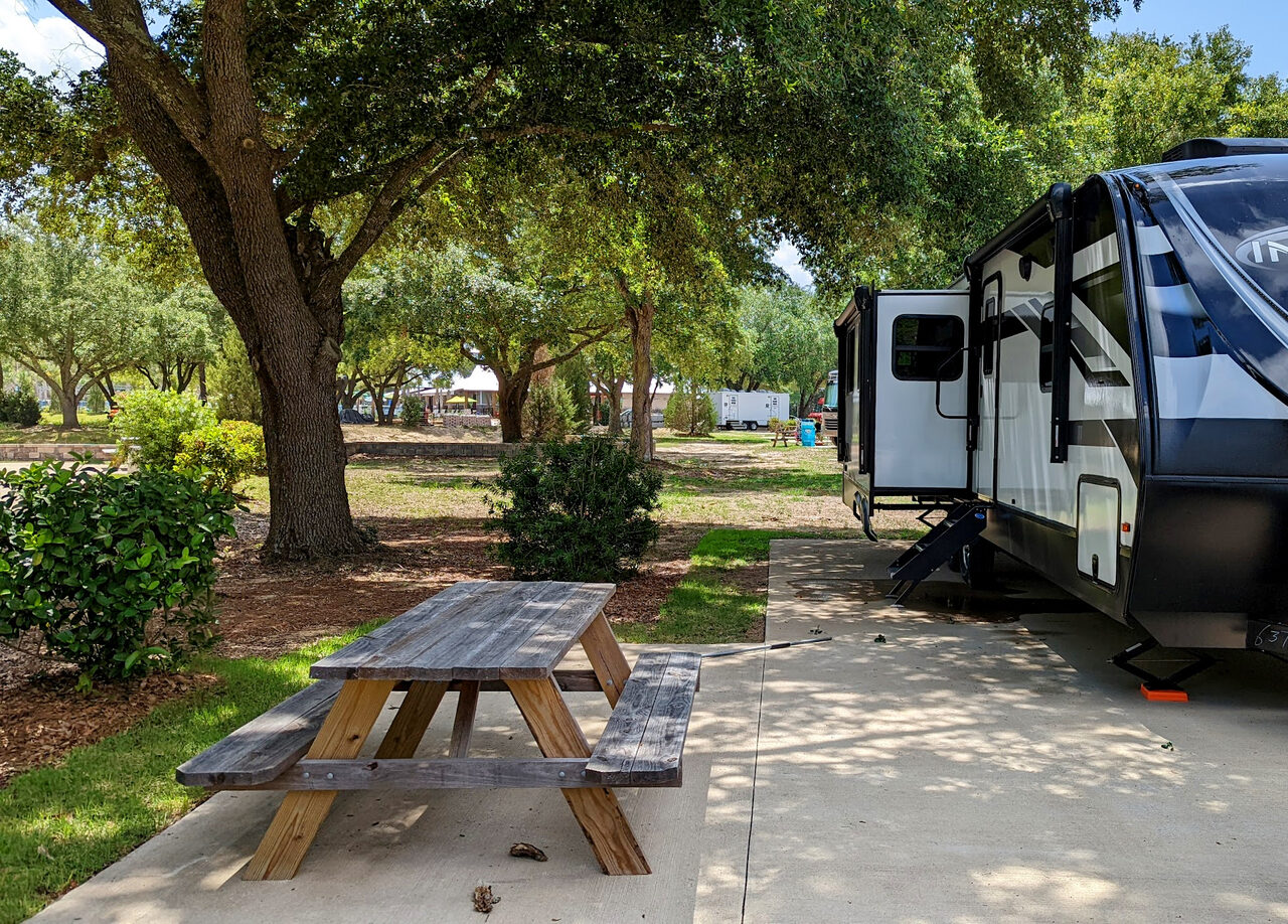 A fifth-wheel RV set up on a shaded all-concrete site at Splash RV Resort in Milton FL