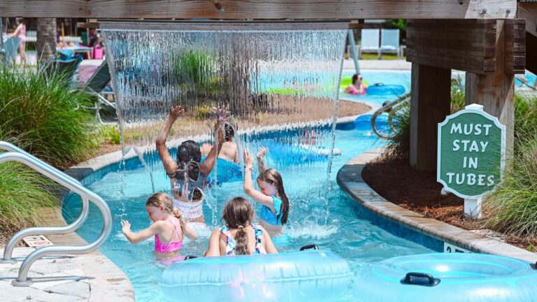 Children playing under the water curtain in the lazy river at Splash RV Resort, a family RV resort in Florida near Navarre Beach
