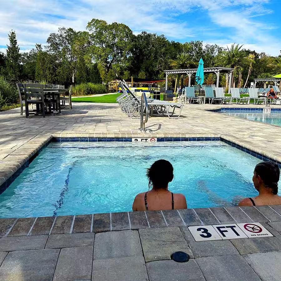 Adults relaxing in the hot tub spa overlooking the pool at Splash RV Resort near Pensacola FL