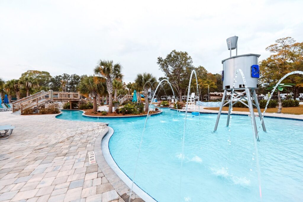 Splash pad and water feature beside the pool with RV sites in the background at Splash RV Resort