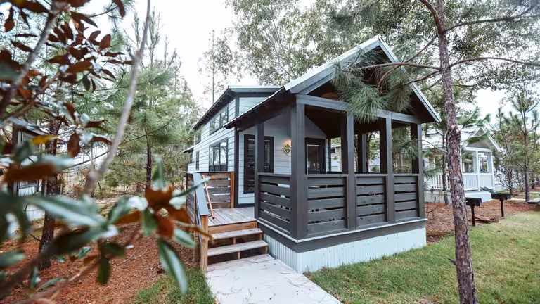 Splash RV Resort luxury cottage with a covered porch among tall pines near Fort Walton Beach