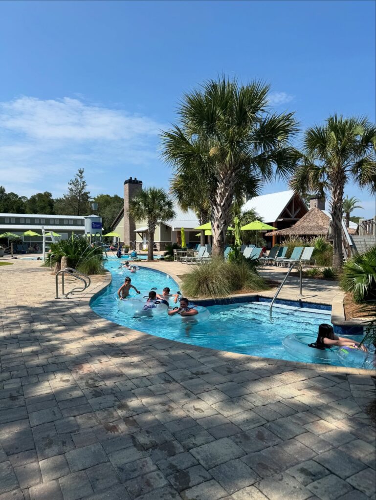 Lazy river winding past palms and a tiki hut at Splash RV Resort near the Emerald Coast