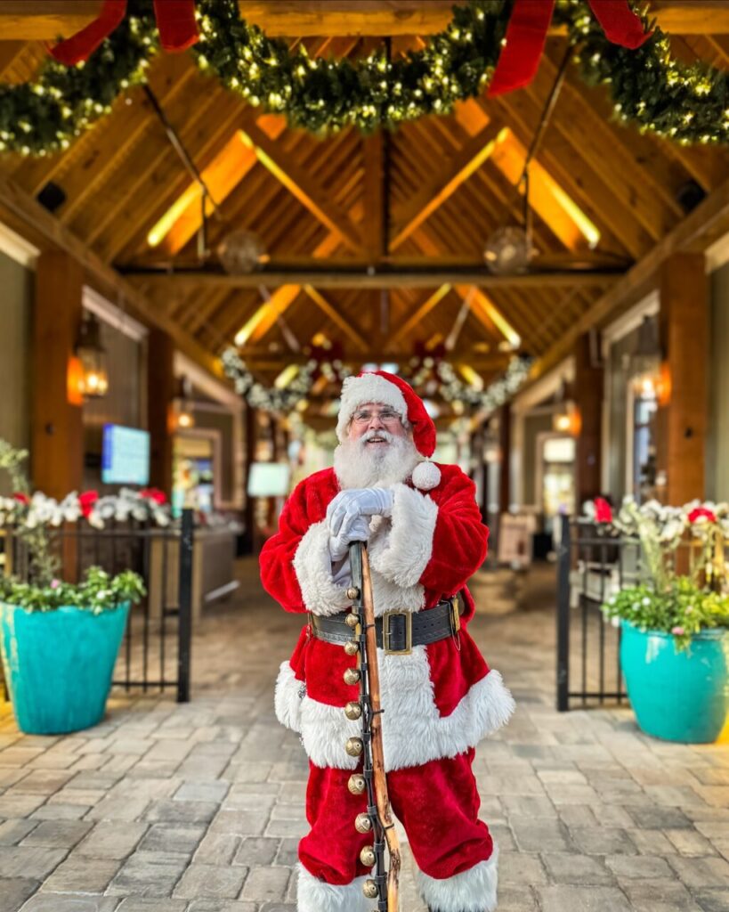 Santa visiting Splash RV Resort near Pensacola FL under lit holiday garland during Christmas season
