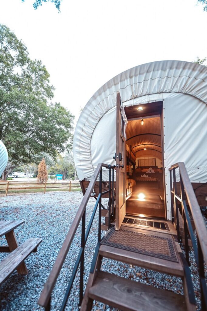 Covered wagon glamping unit with open door at Splash RV Resort in Milton FL