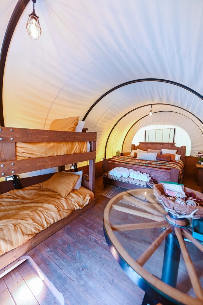 Inside a Conestoga covered wagon with a king bed and bunk beds near Navarre Beach