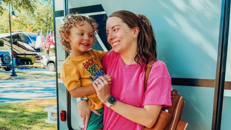 A mom and her toddler smiling beside their RV at Splash RV Resort, an RV park near Pensacola Beach in Milton FL