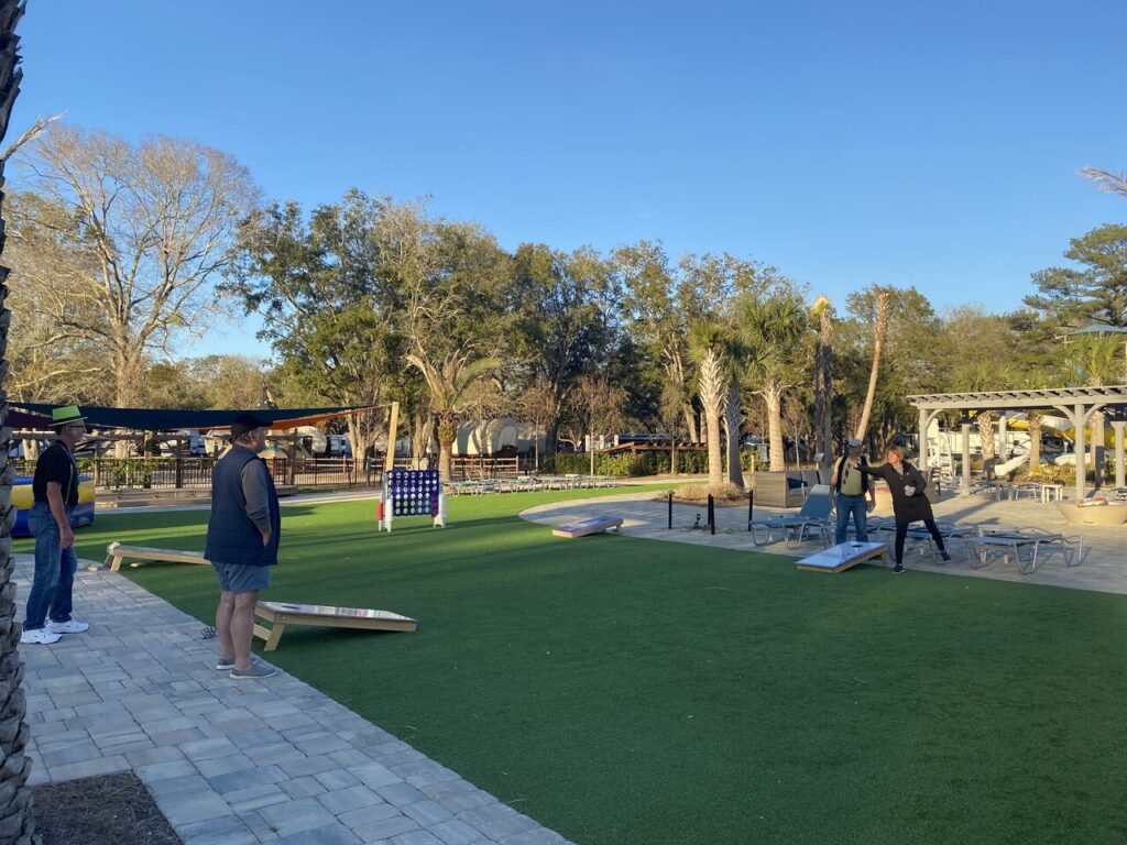 Guests playing cornhole on the lawn at Splash RV Resort near Pensacola in late afternoon light