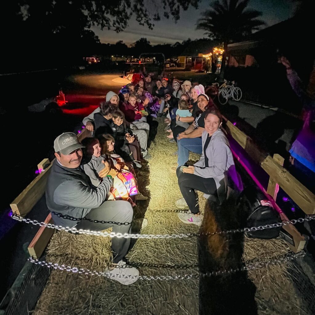 Families seated on hay bales during a nighttime hayride at Splash RV Resort near Pensacola