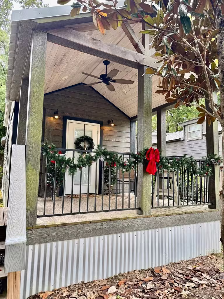 Christmas Cottage porch with a wreath, garland and red bow at Splash RV Resort