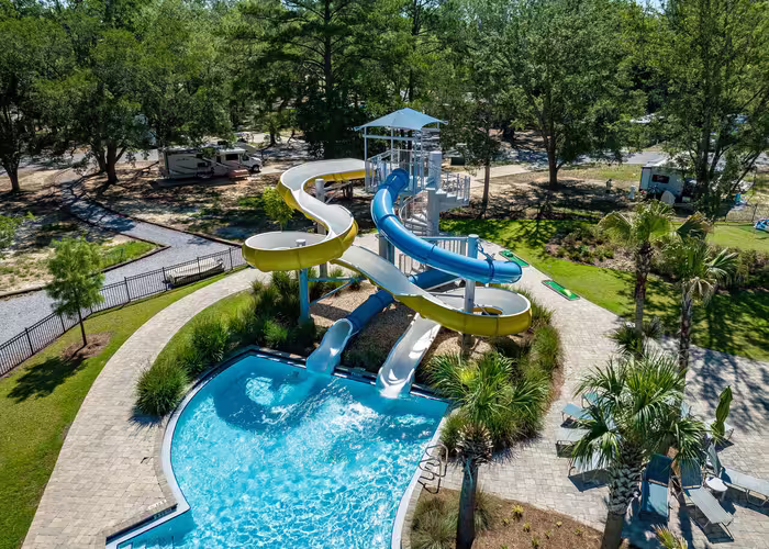 Aerial view of Splash RV Resort's water slides and pool area, surrounded by palm trees and lounge chairs.