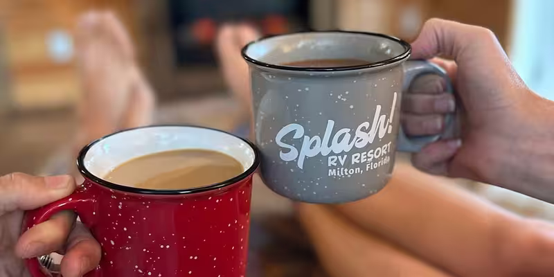 Guests toast with coffee mugs inside a luxury cottage at Splash RV Resort, relaxing before a cozy fireplace.