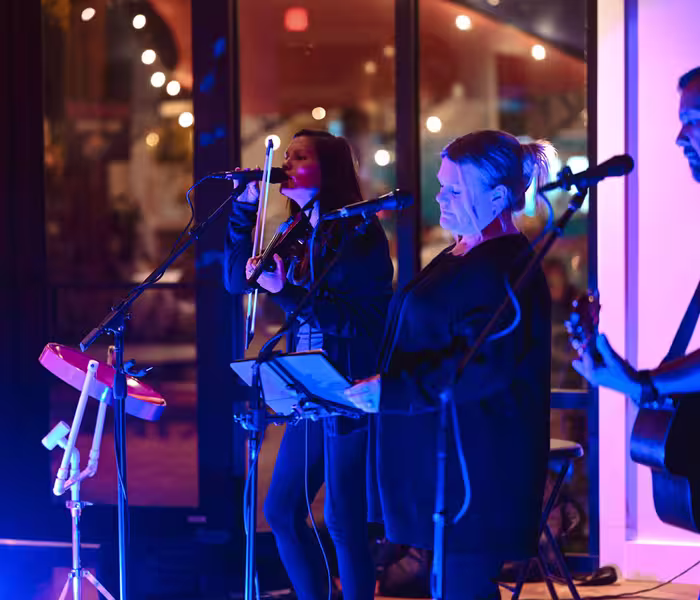 Live band performing on stage at Splash RV Resort, featuring a violinist and vocalists under blue and magenta stage lighting.