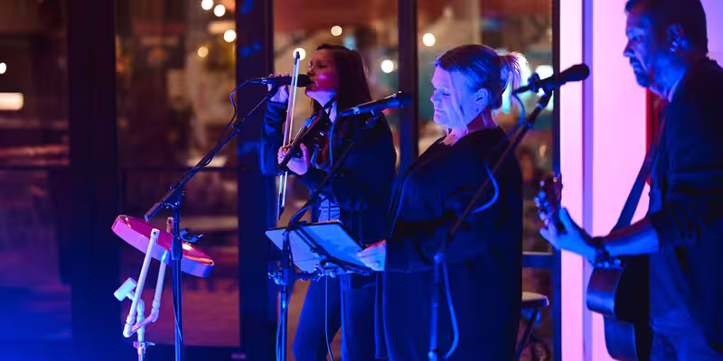 Live band performing on stage at Splash RV Resort, featuring a violinist and vocalists under blue and magenta stage lighting.