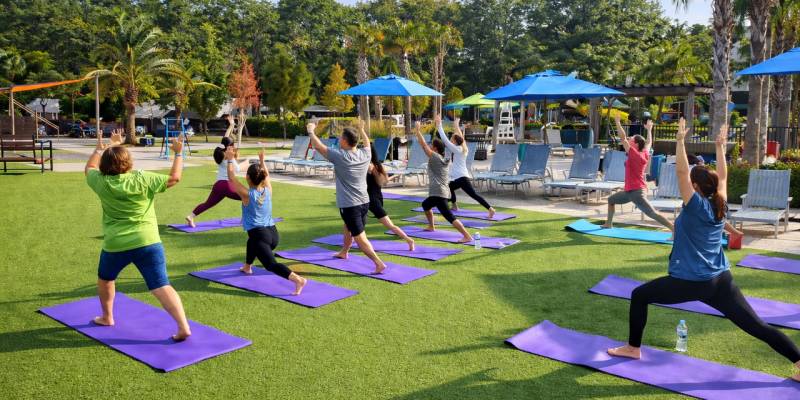 Guests practicing yoga on purple mats on a green lawn at Splash RV Resort.