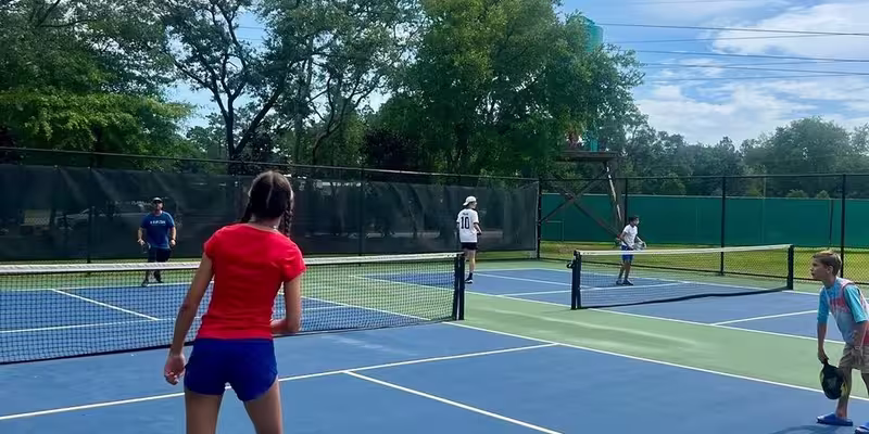 Pristine tennis courts surrounded by lush greenery offer resort-style recreation under brilliant Florida skies