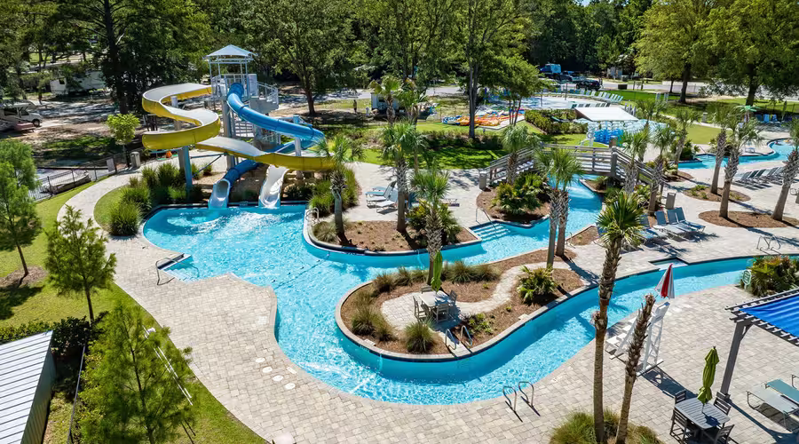 Aerial view of Splash RV Resort water attractions featuring twisting yellow and blue slides, a winding lazy river, and pool