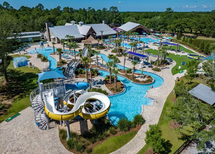 Aerial view of Splash RV Resort's water attractions featuring a yellow water slide, lazy river, and swimming pool.