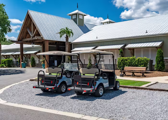Two utility golf carts parked on gravel in front of the Splash RV Resort clubhouse.