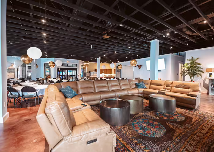 Spacious Splash RV Resort event lounge with tan leather sectional seating and party decorations.