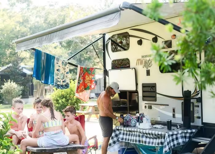 Family grilling and relaxing at their RV site with a picnic table under the awning at Splash RV Resort.