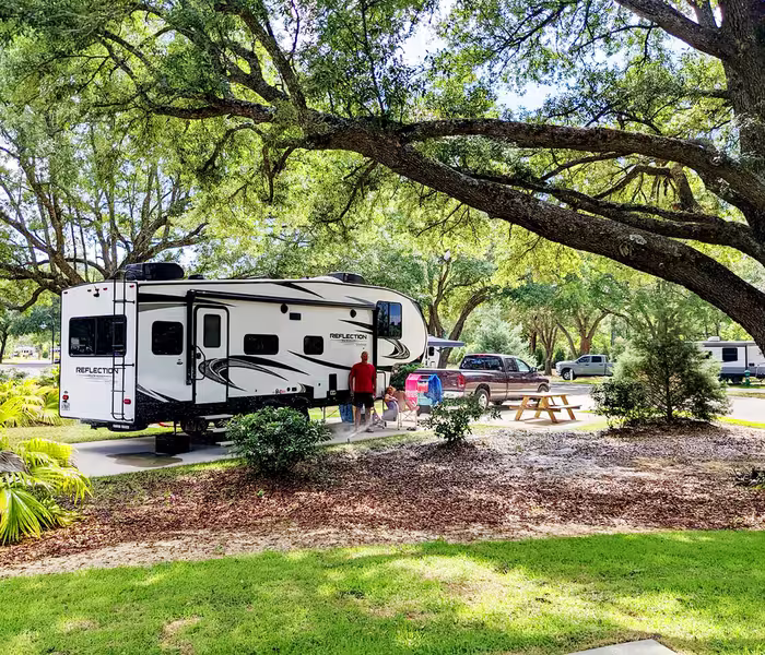 Fifth-wheel RV parked on a shaded site at Splash RV Resort with family and pickup truck nearby