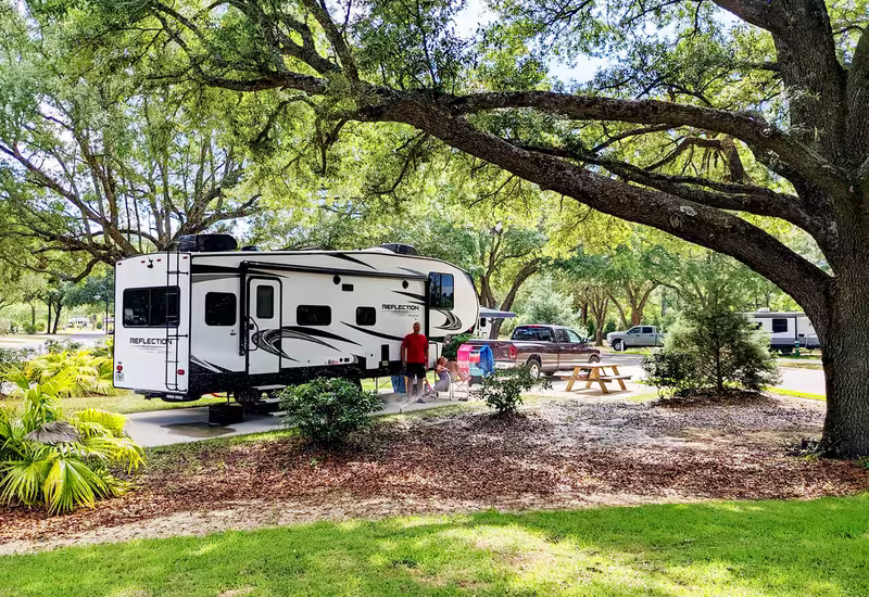 Fifth-wheel RV parked on a shaded site at Splash RV Resort with family and pickup truck nearby