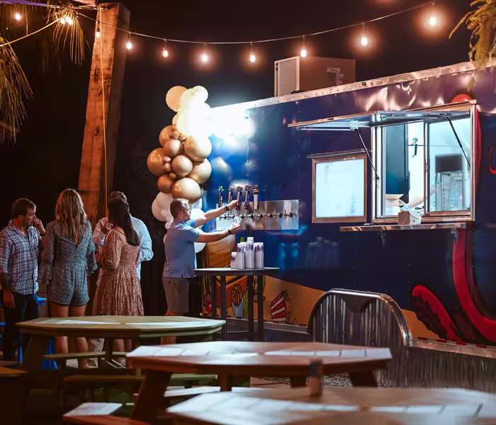 Guests gather around a blue food truck with octopus artwork at Splash RV Resort, enjoying drinks from the tap system under