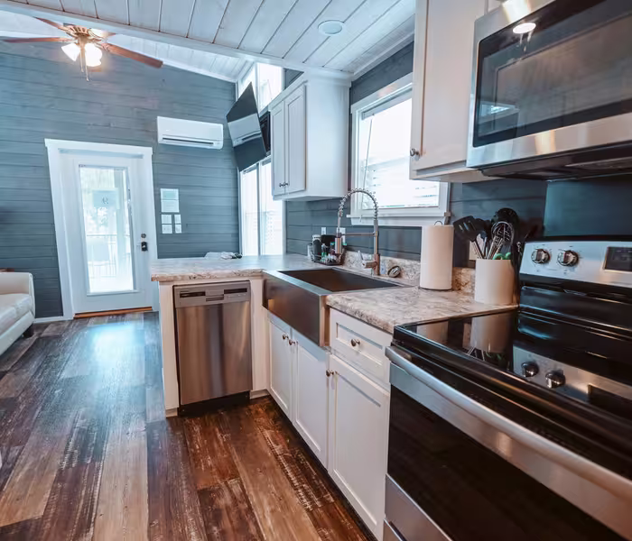Galley kitchen with stainless appliances, farmhouse sink, and granite countertops at Splash RV Resort in Milton, Florida.