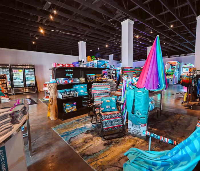 Interior of the Splash RV Resort gift shop and arcade, featuring camping gear, apparel, snacks, and games.