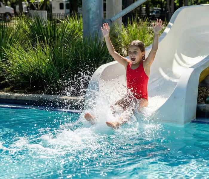 Girl splashing into pool at Splash RV Resort Milton after riding a water slide