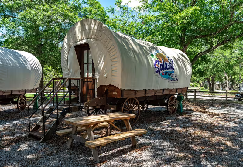 A beige glamping wagon with a picnic table at Splash RV Resort