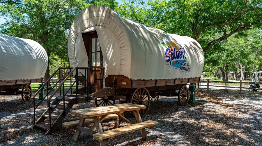 A beige glamping wagon with a picnic table at Splash RV Resort