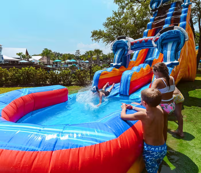 Children play on a towering blue and orange inflatable water slide at Splash RV Resort in Milton, Florida
