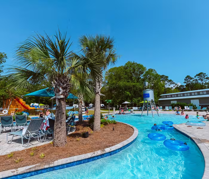 Guests float on tubes in the lazy river at Splash RV Resort, with the main pool and water slides in the background.