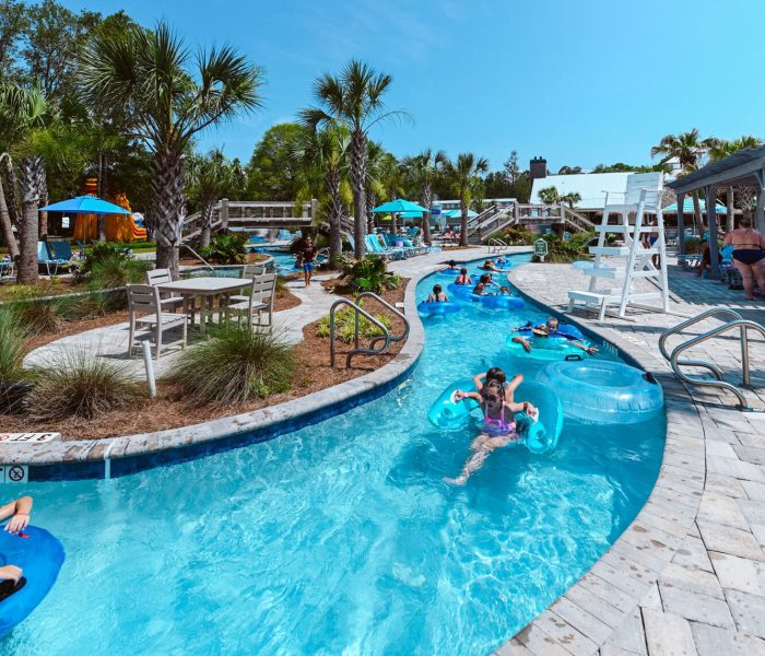 Guests float along the winding lazy river on bright blue inner tubes at Splash RV Resort in Milton, Florida