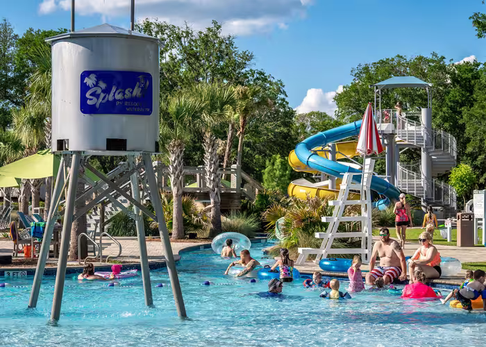 Guests float on tubes in the lazy river near a blue and yellow water slide at Splash RV Resort.